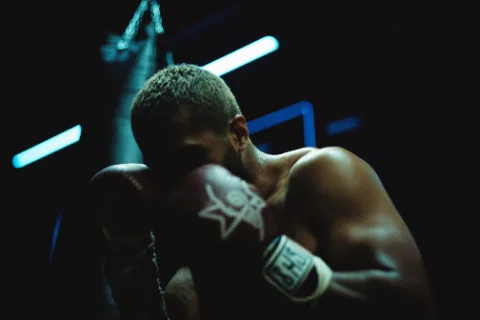 Boxer s rukavicami v tmavej telocvični